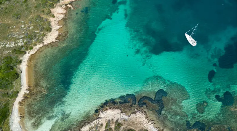 Private boat anchored alone in a turquoise La Maddalena cove