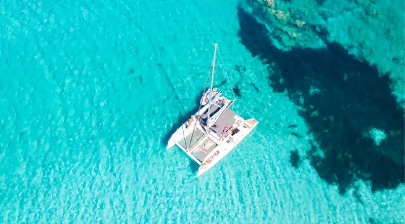 A catamaran anchored over turquoise water in the La Maddalena Archipelago