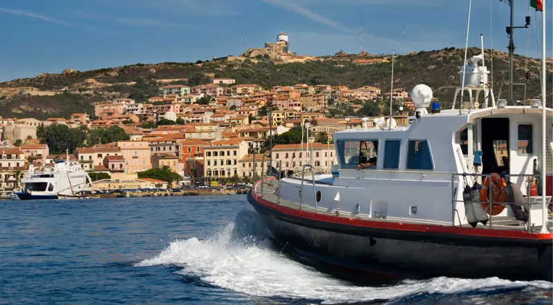 A full-day group tour boat cruising past La Maddalena town