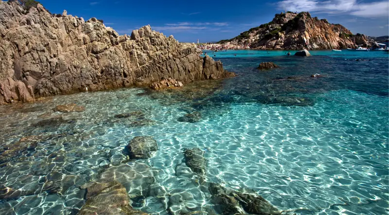Pink granite rocks meeting turquoise water in the La Maddalena Archipelago