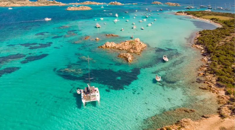 Boats over the turquoise Porto della Madonna natural pools near Razzoli, La Maddalena