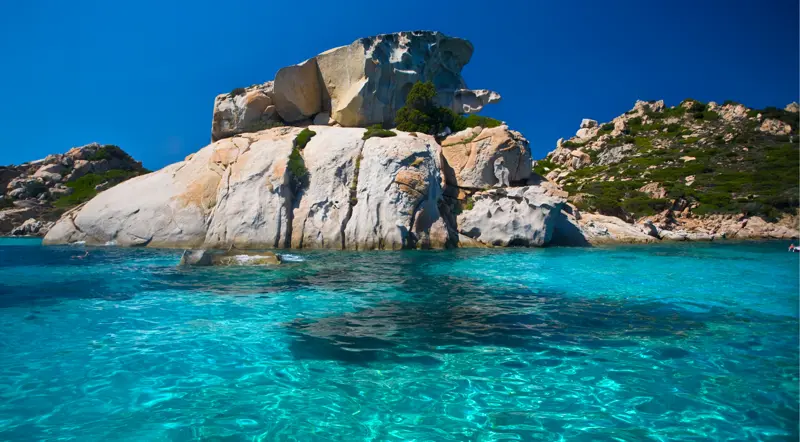 Wind-sculpted granite rock formations rising from clear water at Spargi